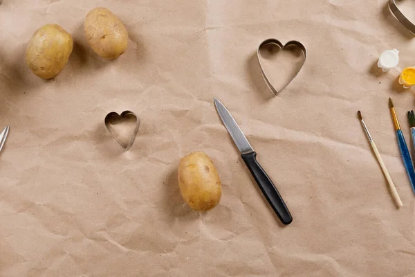 heart shaped potato stamp on craft paper. The process of decorating a gift for Valentines Day. Getting ready for the celebration on February 14th.