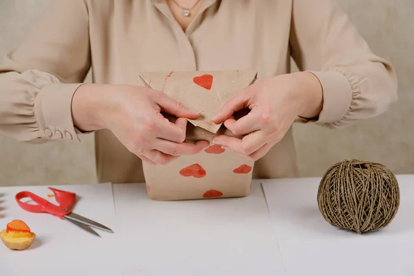 Sello de patata en forma de corazón en papel artesanal. El proceso de decorar un regalo para el Día de San Valentín. Preparándose para la celebración del 14 de febrero. — Foto de Stock