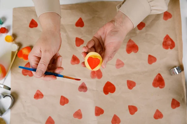 Herzförmige Kartoffelmarke auf Bastelpapier. Der Prozess der Dekoration eines Geschenks zum Valentinstag. Vorbereitungen für das Fest am 14. Februar. — Stockfoto