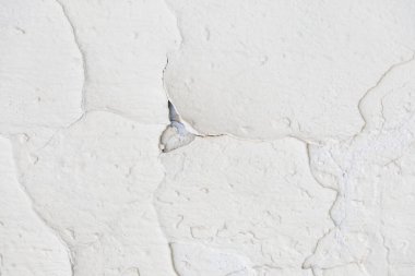 Çatlakları ve soyulmuş boyası olan beyaz eski bir duvarın dokusu