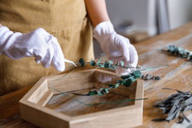 Dekorasyon süreci bunu kendi başına yapıyor. Kadınlar küçük bir ev atölyesinde çiçeklerle çalışır. Girişimcilerin yaşam tarzı konsepti. Botanik bitkileri olan ahşap çerçeveler.
