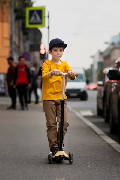 Мальчик ездит на скутере по городу. — стоковое фото
