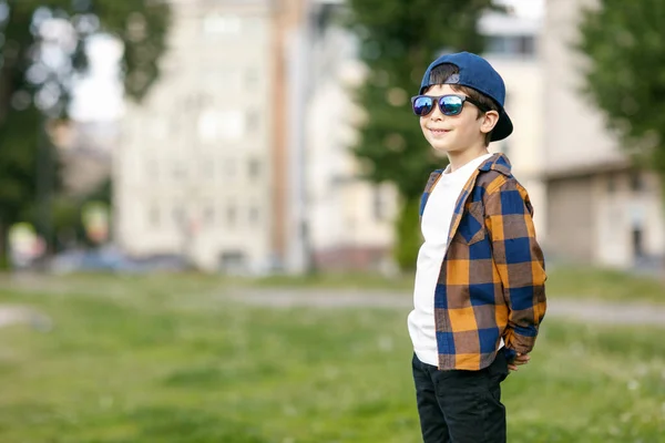 Un chico en la ciudad con gafas de sol. Bebé juega con burbujas de jabón — Foto de Stock