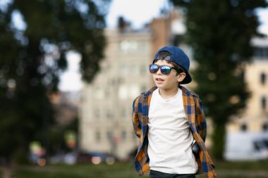 Kasabada güneş gözlüğü takan bir çocuk. Bebek sabun köpüğüyle oynuyor
