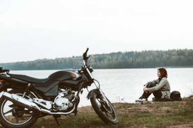 Doğada motosikletli bir kadın. Motosikletli ormanda yürüyor.