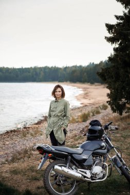 Doğada motosikletli bir kadın. Motosikletli ormanda yürüyor.