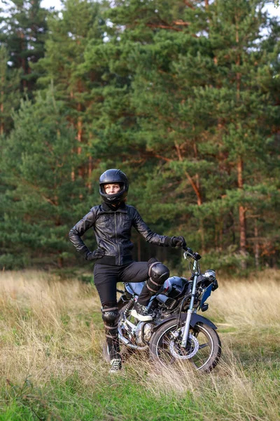 Seorang wanita mengendarai sepeda motor di alam. Pengendara sepeda motor berjalan melalui hutan — Stok Foto