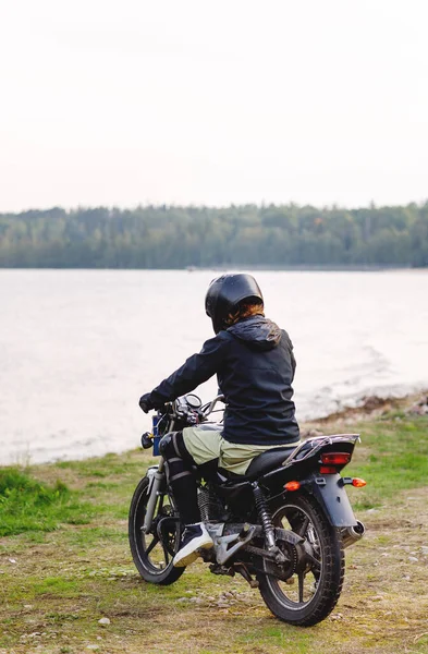 Dziewczyna rowerzysta w czarne ubrania i czarny kask na motocyklu — Zdjęcie stockowe