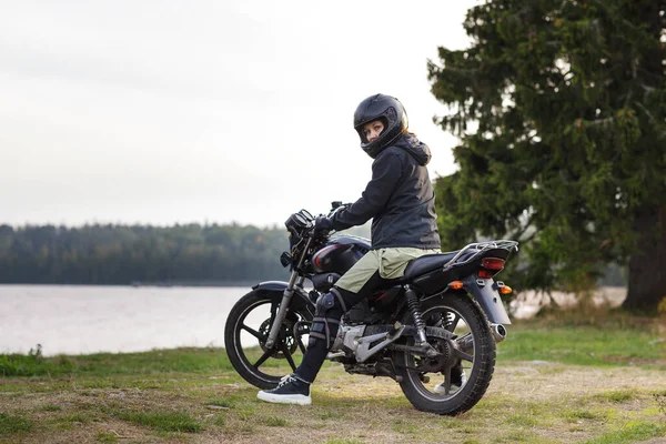 Biker dívka v černém oblečení a černé helmy na motorce Stock Fotografie