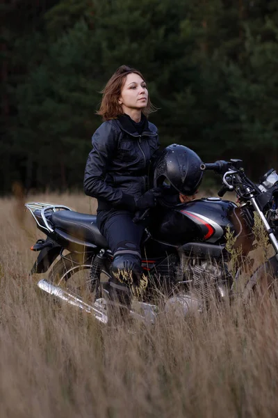 Seorang wanita mengendarai sepeda motor di alam. Pengendara sepeda motor berjalan melalui hutan — Stok Foto