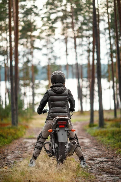 Seorang wanita mengendarai sepeda motor di alam. Pengendara sepeda motor berjalan melalui hutan — Stok Foto