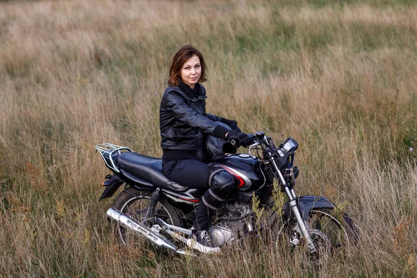 Seorang wanita mengendarai sepeda motor di alam. Pengendara sepeda motor berjalan melalui hutan — Stok Foto