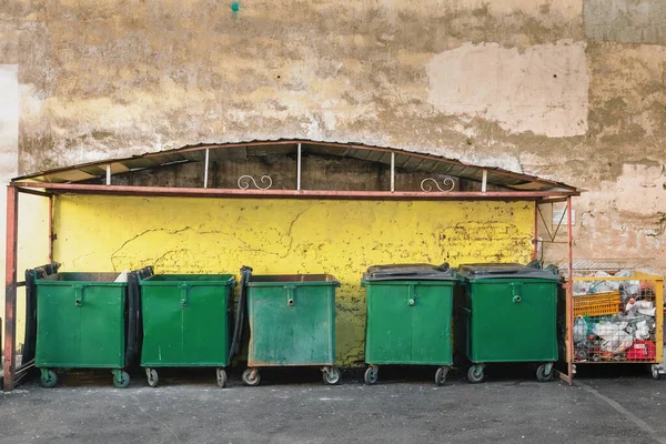 Bidoni della spazzatura. bidoni verdi della spazzatura su sfondo giallo parete — Foto Stock