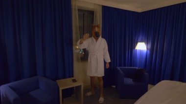 At maskeli bir adam işten sonra 4K ağır çekim 60fps ile rahatlıyor ve viski içiyor.