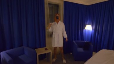 At maskeli bir adam işten sonra 4K ağır çekim 60fps ile rahatlıyor ve viski içiyor.