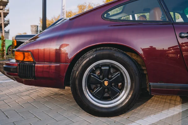 Vilnius, Litvanya - 2025-09-20 - Porsche 'nin altın logosuyla arka tekere yakın çekim ve klasik Porsche 911' in çamurluğu