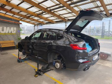 Vilnius, Litvanya - 2025-07-14 - Lastik servisi ve sezonluk hazırlık: Bir lastik atölyesinde lastik değiştirme sırasında tekerleksiz duran modern BMW X4