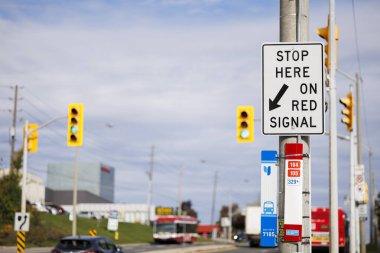 Trafik işaretleri ve etkin bir caddenin geniş bir bölümü tarafından çerçevelenen ve kentsel hareket kontrolünü vurgulayan 