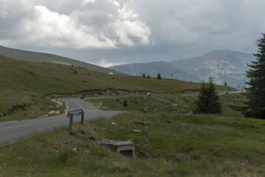Romanya Transalpina yolunun sık orman ve dağlık arazide kıvrılan manzaralı bir uzantısı. Yayın, seyahat, altyapı veya doğa fotoğrafçılığı temaları için ideal.