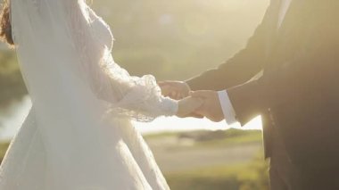 El ele tutuşan tanınmayan genç adam ve kadın. Yüzüklerimizi değiş tokuş ettikten sonra ayakta duran yeni evli bir çift. Mutlu evlilik çifti. Romantik bir ilişki. Beyaz elbise