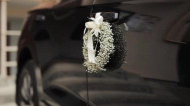 Düğün arabası, düğün çiçekleri ve saten kurdelelerle süslenmiş. Düğün Dekorasyonu. Düğün Dekorasyonları Tasarımı. Düğünde çiçekler modern arabada.