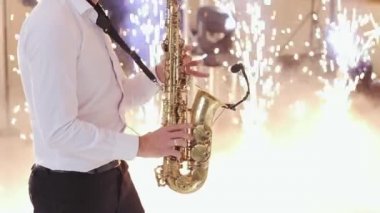Saksafoncu düğünde solo performans sergiliyor. Saksafoncu, altın saksafonda çalıyor. Canlı performans. Bir konserde alto saksafon çalan müzisyen. Düğün günü. İlk düğün dansı.