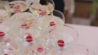 Masasında iki şişe şampanya bardağı olan bir kule. Garson cam kuleye şampanya döker. Yeni yıl partisi için gözlük piramidi. Şampanya kulesinin restoranı arka planda.