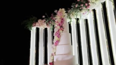 Masada çiçekler olan düğün pastası. Düğün gecesi beyaz meyveli düğün pastası. Düğün günü çiçekli düğün kemeri.