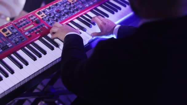 Musiker, der auf den Keyboard-Synthesizer-Klaviertasten spielt. Musiker spielt auf der Konzertbühne ein Musikinstrument. Männer in Schwarz spielen im Nachtclub Jazz, Soul und Chill-Out-Songs. Entspannte Atmosphäre. — Stockvideo