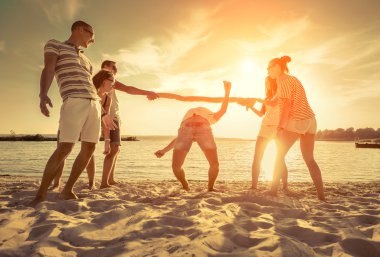 Dostlar gün batımında sahilde komik bir oyun oynar..