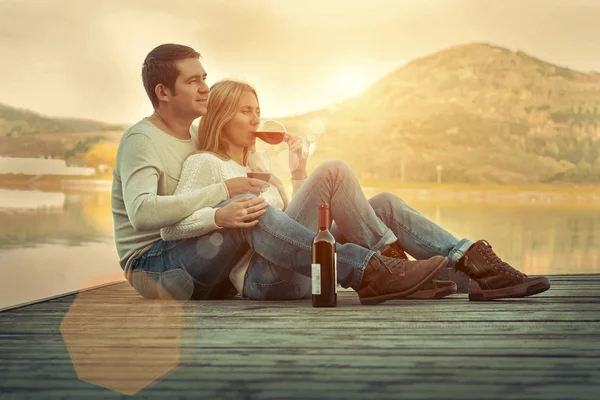 Couple assis sur la jetée avec du vin rouge — Photo