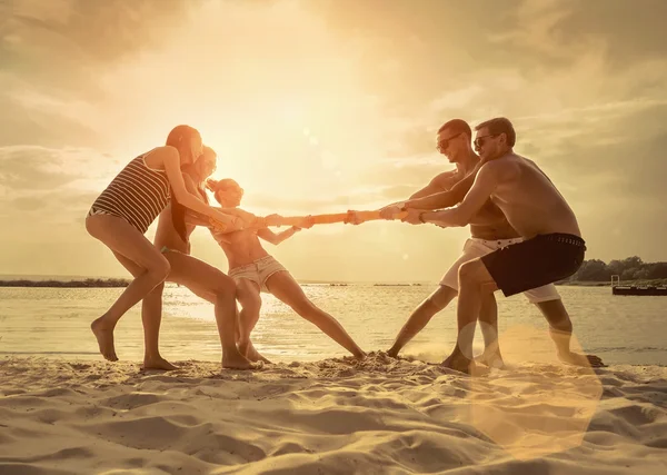 日没の太陽の下でビーチでの戦争の友人面白い綱引き — ストック写真
