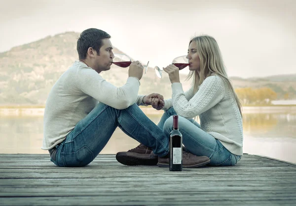 Paar sitzt mit Rotwein auf der Seebrücke — Stockfoto