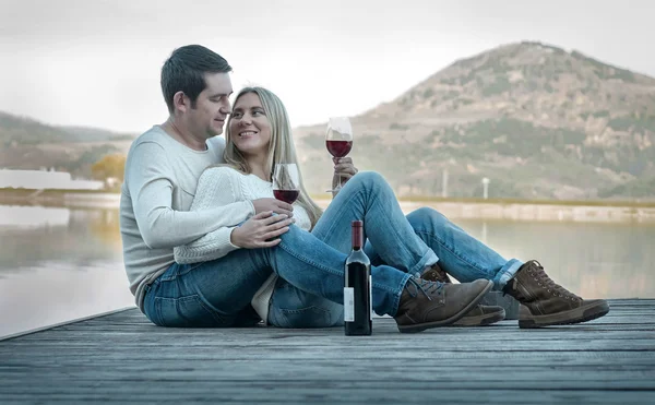 Paar sitzt mit Rotwein auf der Seebrücke — Stockfoto