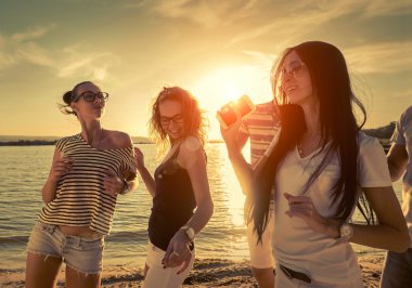 Günbatımı güneş ışığı altında sahilde arkadaşlar komik dans.