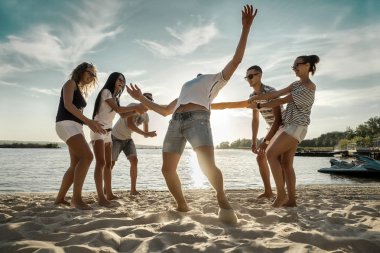 Dostlar gün batımında sahilde komik bir oyun oynar..