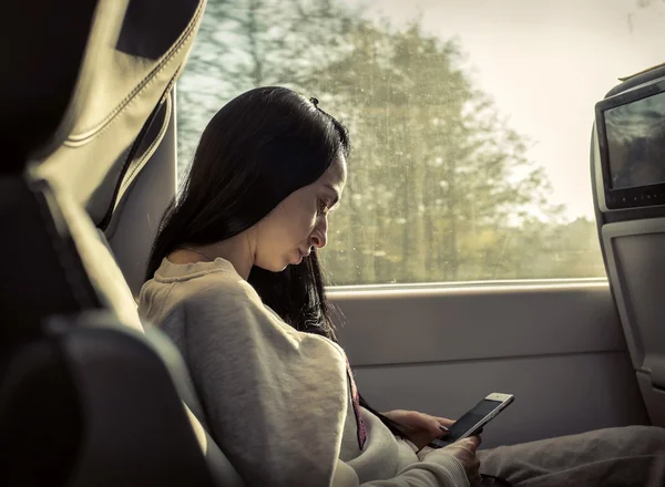 Mujer sentada en tren con teléfono móvil — Foto de Stock