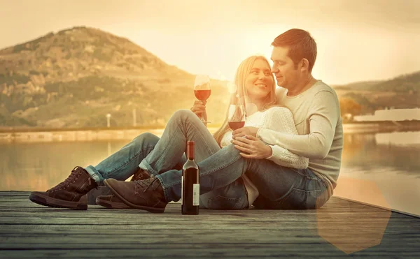 Couple assis sur la jetée avec du vin rouge — Photo