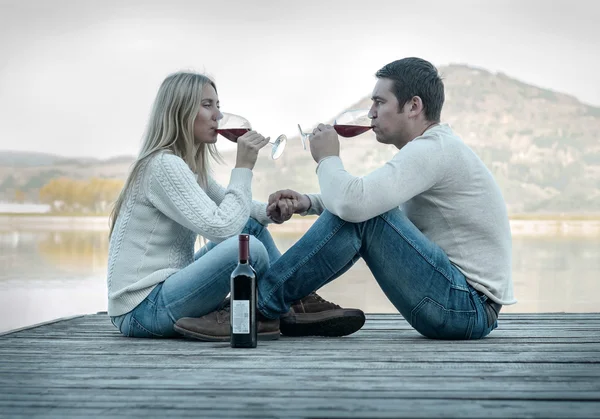 Paar sitzt mit Rotwein auf der Seebrücke — Stockfoto