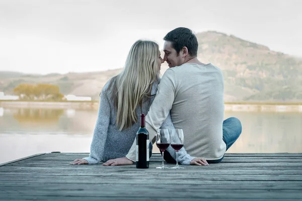 Пара сидить на пірсі з червоним вином — стокове фото