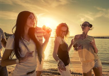 Günbatımı güneş ışığı altında sahilde arkadaşlar komik dans.