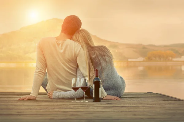 Paar sitzt mit Rotwein auf der Seebrücke — Stockfoto