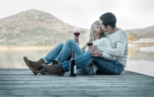 Couple sitting on the pier with red wine — Stock Photo, Image