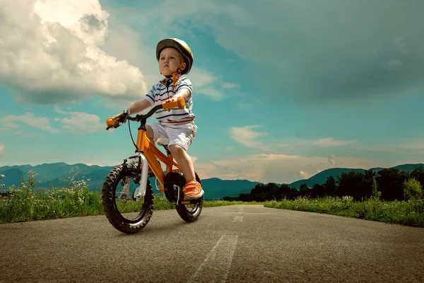 Kind op oranje fiets — Stockfoto