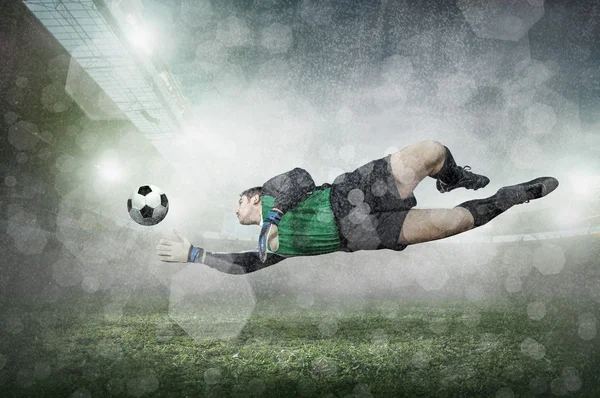 Joueur de football avec ballon en action au stade sous la pluie . — Photo