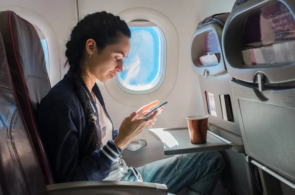 Frau mit Handy im Flugzeug. — Stockfoto