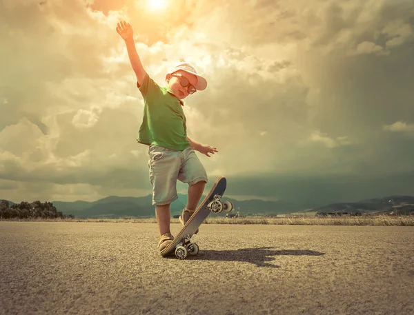 Niño con monopatín bajo la luz del sol . — Foto de Stock