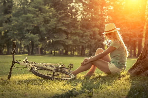 Femme assise près de son vélo — Photo