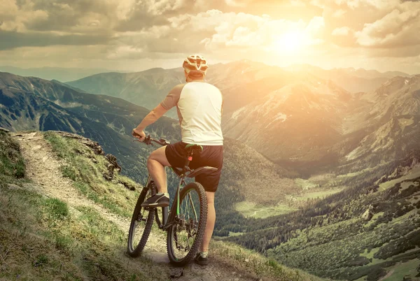 Homem com bicicleta aroun montanhas — Fotografia de Stock