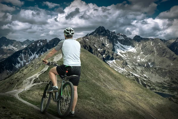 Человек с велосипедом в горах — стоковое фото